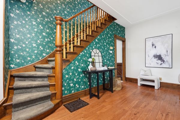 Curving heritage staircase with green floral wallpaper