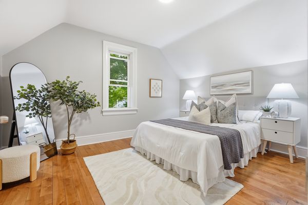Staged upstairs bedroom with light-filled window and mirror