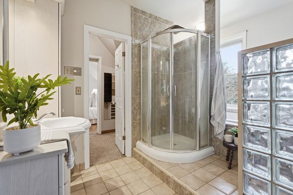 Full bathroom with curved glass shower and glass block wall